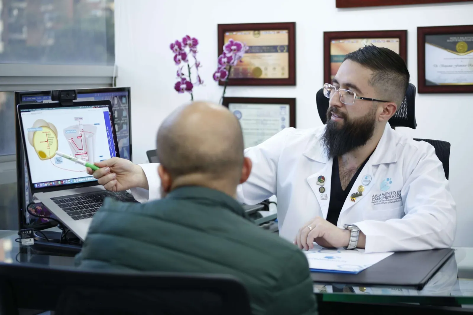 El Dr. Benjamín Ramírez explica una lámina a un paciente en su consultorio.
